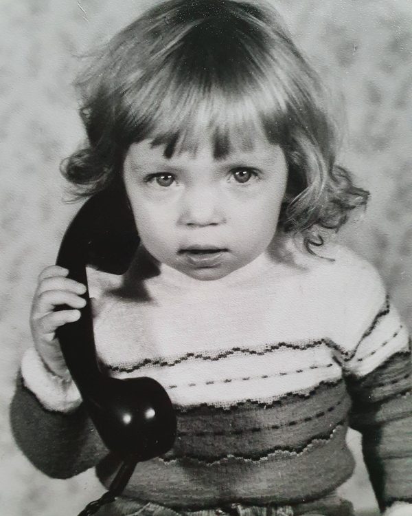 Anja als kleines Mädchen mit einem Telefonhörer am Ohr