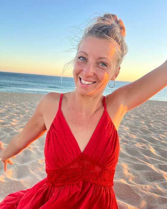 Anja lachend im roten Kleid am Strand bei Sonnenuntergang