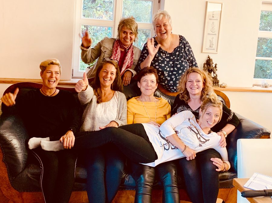Anja mit einer lachenden Seminargruppe auf einem Sofa